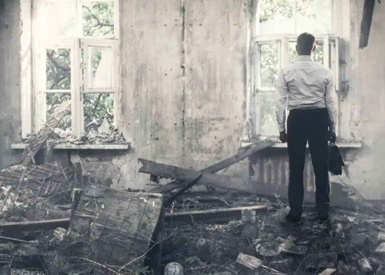 a man standing in a destroyed building looking out a window