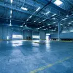 Wide view of an empty modern warehouse with industrial lighting and trucks.